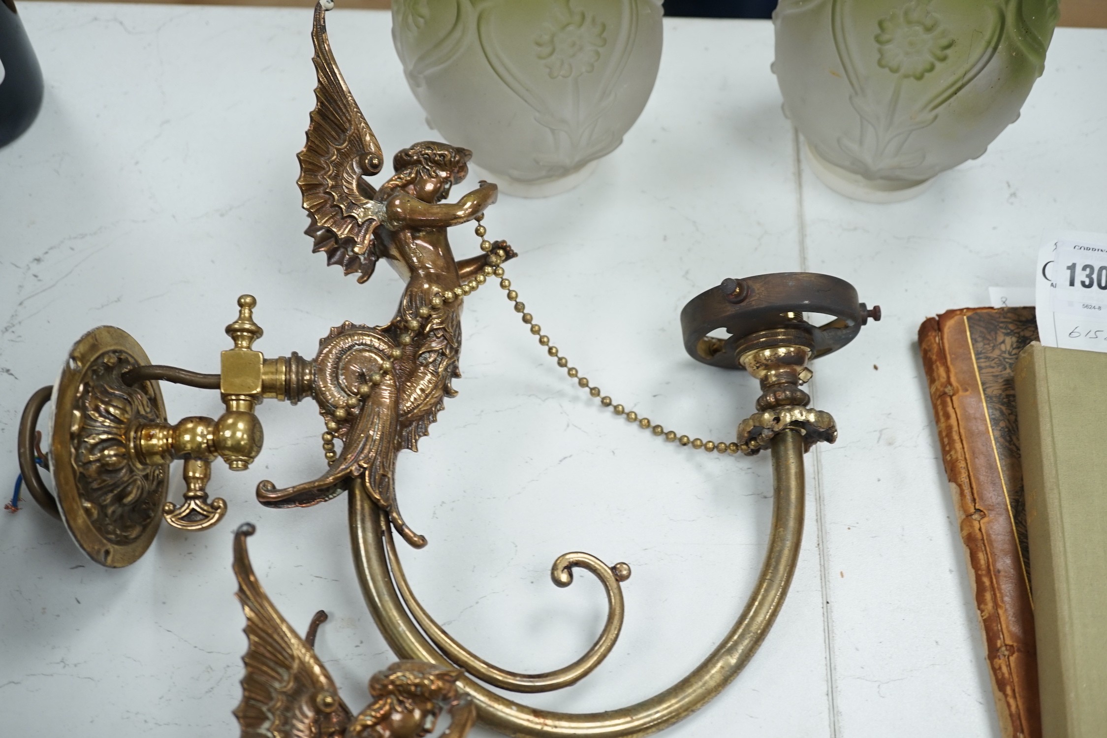 A pair of brass winged caryatid wall lights with green shades, 30cms deep